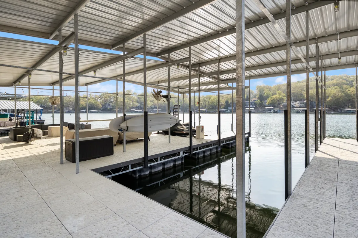 The photo captures a dock area with comfortable seating, a boat moored nearby, and the shimmering surface of the lake. It conveys the social and recreational aspect of lakefront living, with ample space for gearing up or relaxing after a swim or paddle.