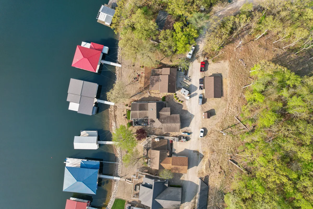 A scenic lakefront scene with colorful boat docks, surrounding greenery, and an unpaved access road leading to a parking area. This view highlights both the recreational aspect of boating and fishing and the natural beauty that defines the area throughout the year.