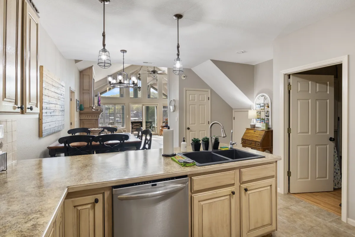 A welcoming, open-plan kitchen and dining area with a kitchen island, spacious dining table, and large windows that invite natural light. Modern lighting and decor provide a warm ambiance, while the layout encourages conversation and shared meals with family or friends.