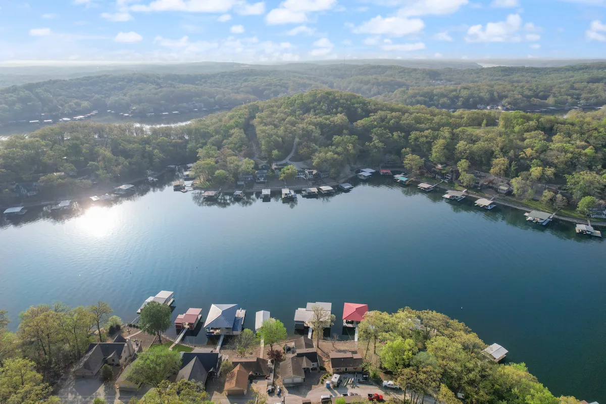 A wide view of the calm lake, surrounded by greenery, docks, and boathouses. The image evokes a sense of peaceful exploration and hints at nearby activities like boating, fishing, and nature walks.
