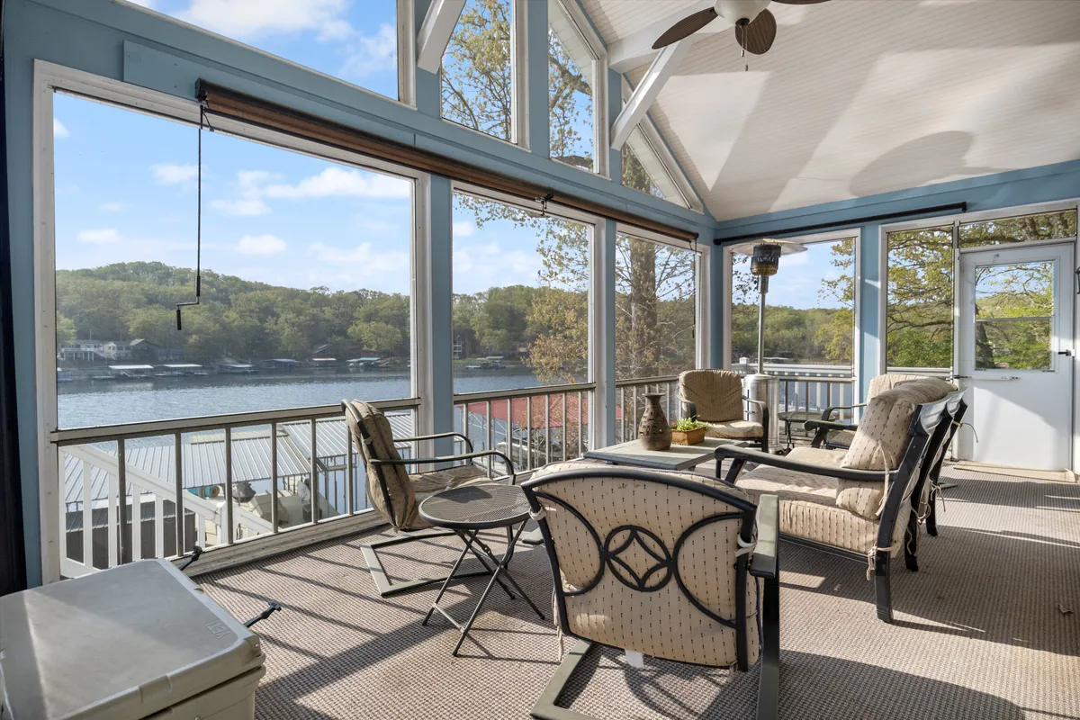 This image captures a bright, tranquil living area featuring large windows that overlook the lake. Comfortable seating is arranged to take advantage of the view, while decorative plants accent the space and natural sunlight fills the room. The setting exudes warmth and connection while highlighting both the plush furnishings and the panoramic vista.
