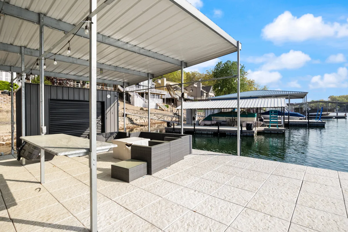 A comfortable lounge seating area sits on the dock, overlooking the sparkling water. The scene captures a casual, serene mood, with the dock and lounge as central features for relaxing by the lake or gearing up for water activities.