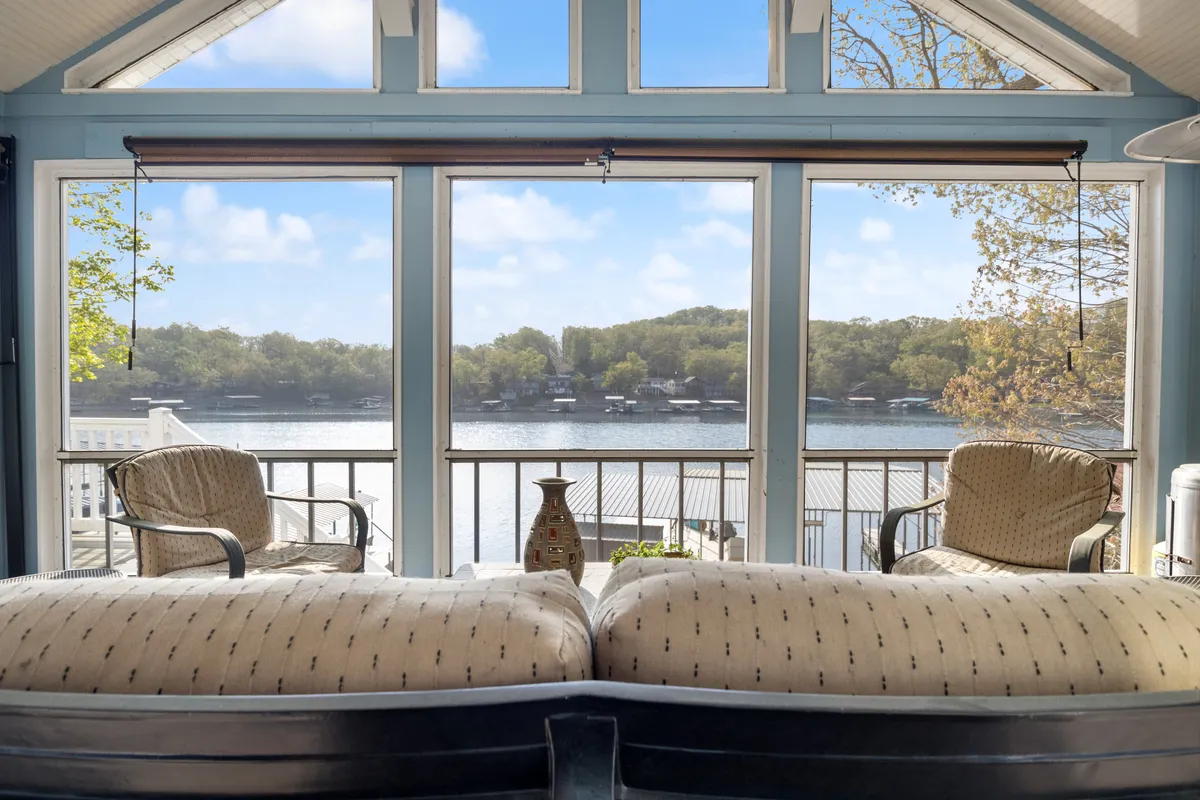A bright, comfortable interior seating space with large windows offering panoramic views of the lake. Decorative elements and plush seating create a relaxing indoor environment that still feels closely connected to the tranquil outdoor scenery.