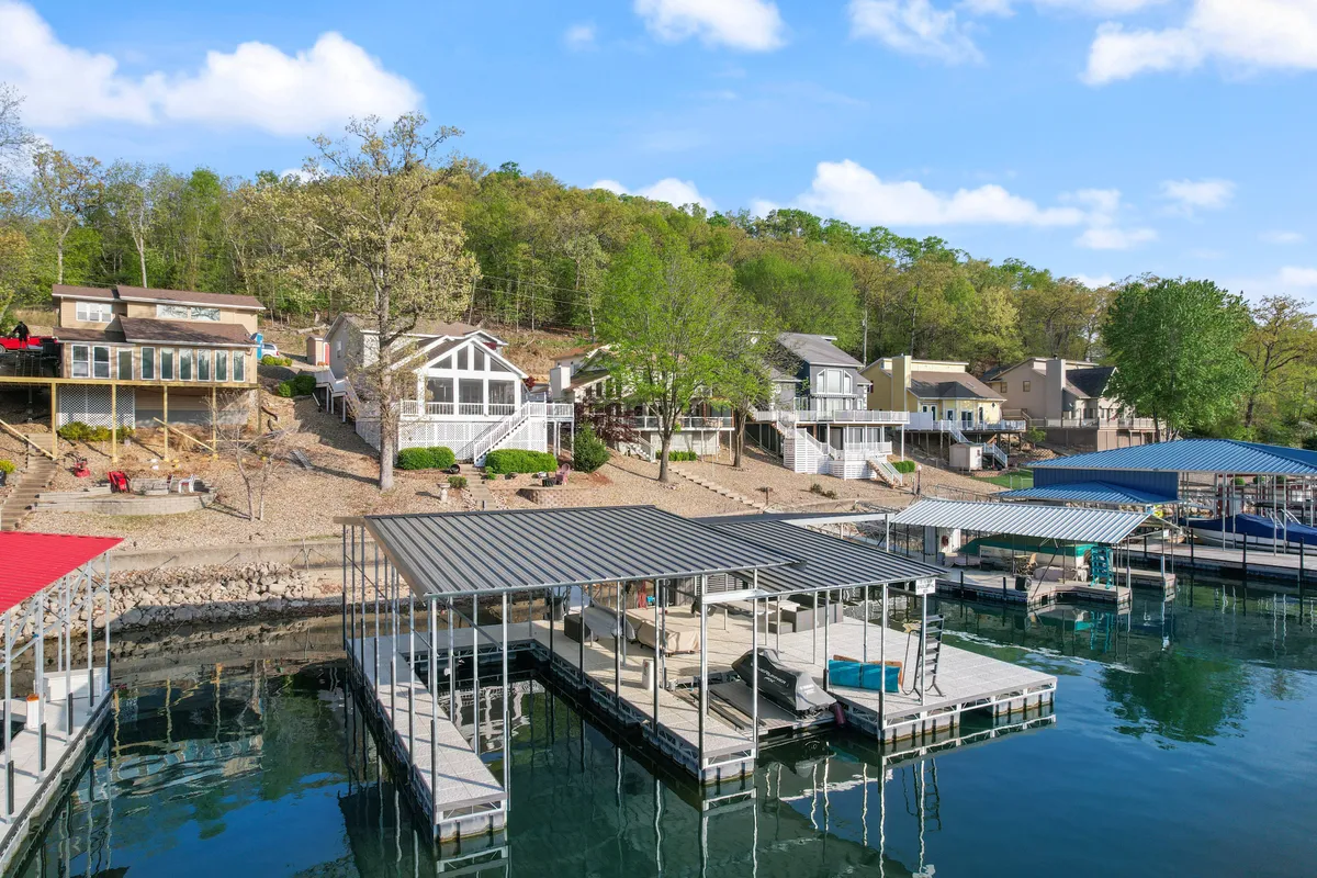 This image features a picturesque lakefront scene with calm waters, several docks (likely private), boats at rest, and lush greenery along the shoreline. The gently sloping hill and serene environment evoke a sense of relaxation and adventure, ideal for families seeking safe, private water fun.